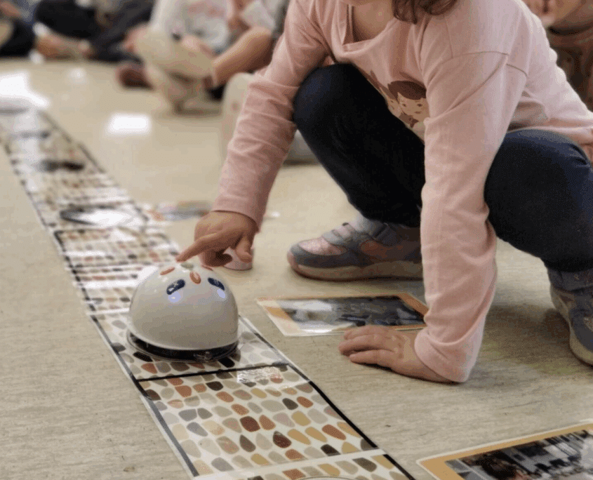 Infant manipulant un robot educatiu sobre una catifa en una activitat d’experimentació i joc creatiu.
