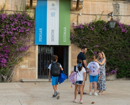 Una família amb infants és rebuda a l’entrada de l’Escola Garbí Pere Vergés de Badalona